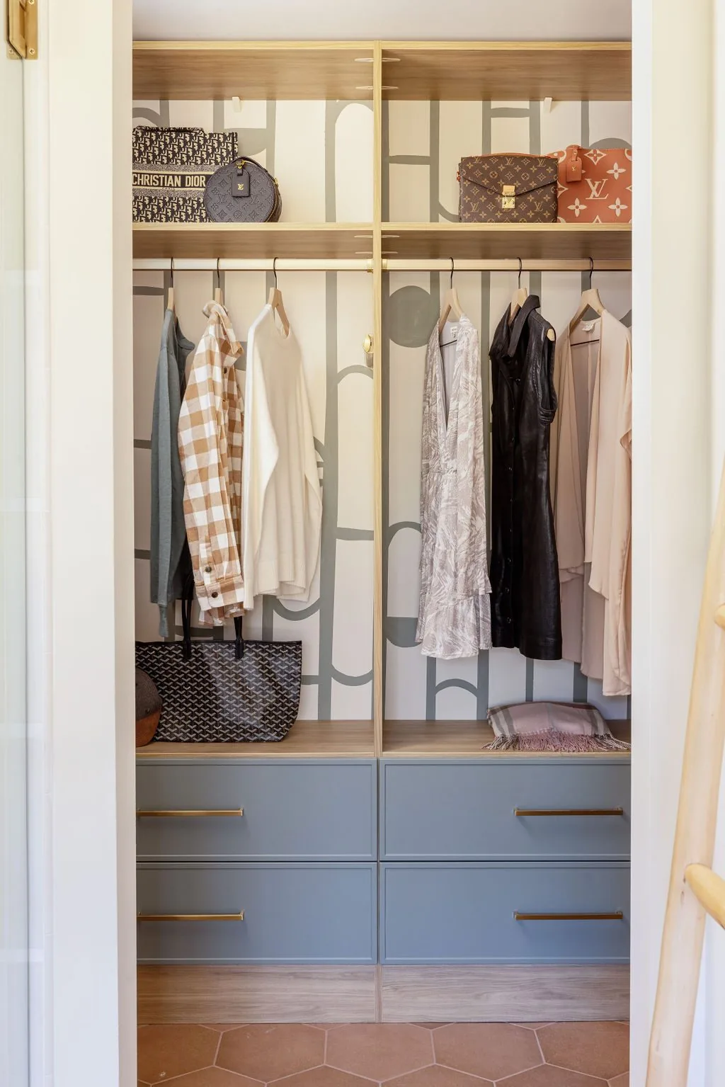 Reach-in wardrobe with soft blue drawer bases and brass pulls