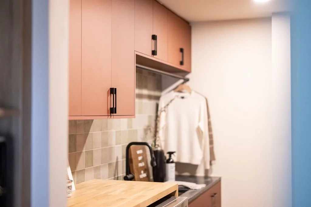 Laundry room cabinetry in terracotta with a wood counter