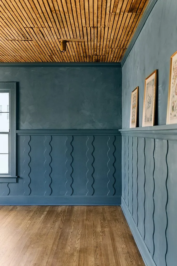 Paneled accent wall in deep green with a slatted wood ceiling