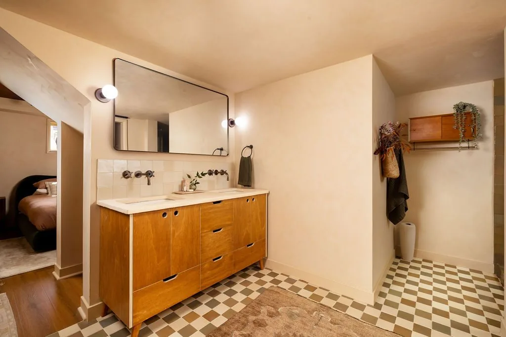 Renovated primary bathroom with a wood double vanity and patterned tile floor